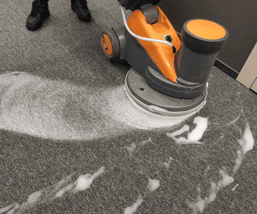 Carpet cleaning machine scrubbing with foam.
