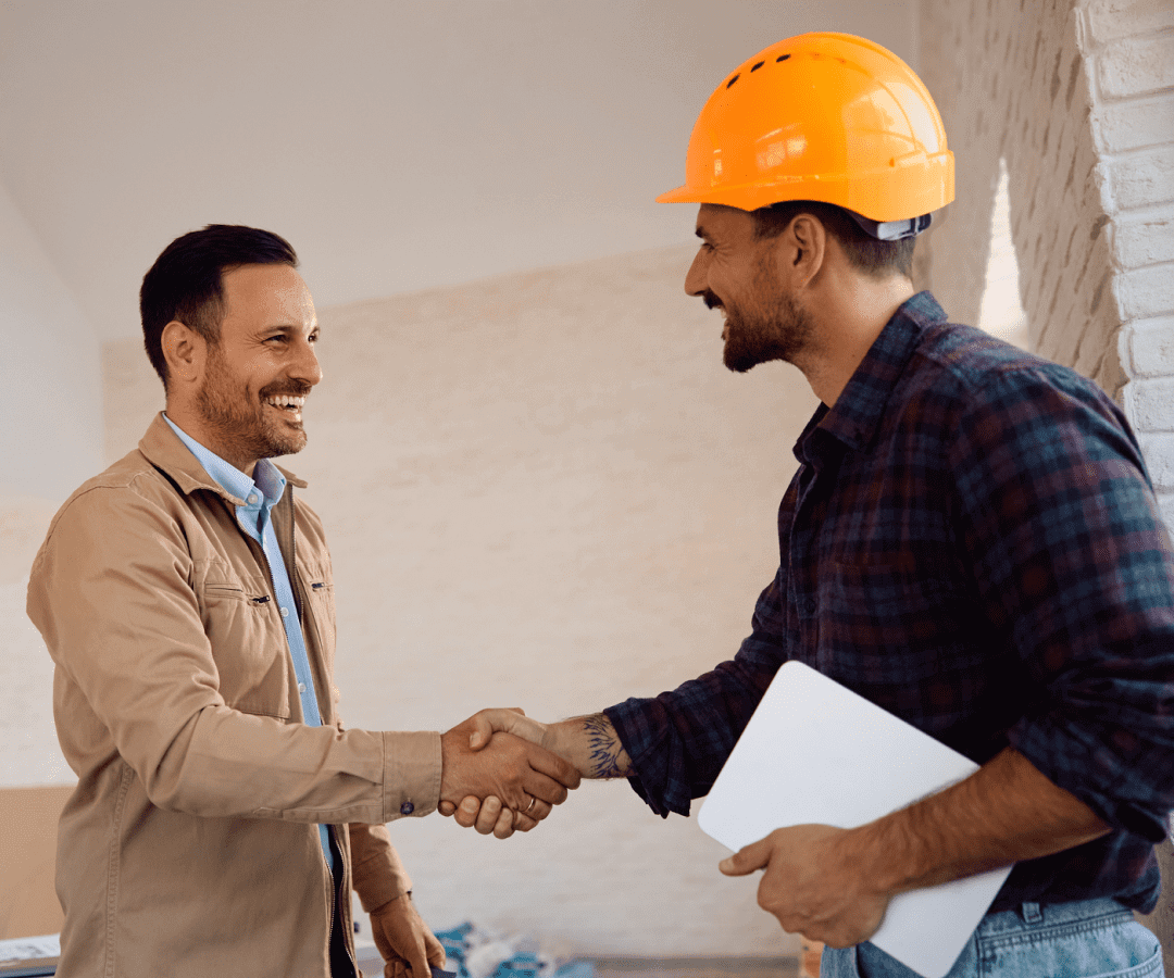 Two men shaking hands, one in hard hat.