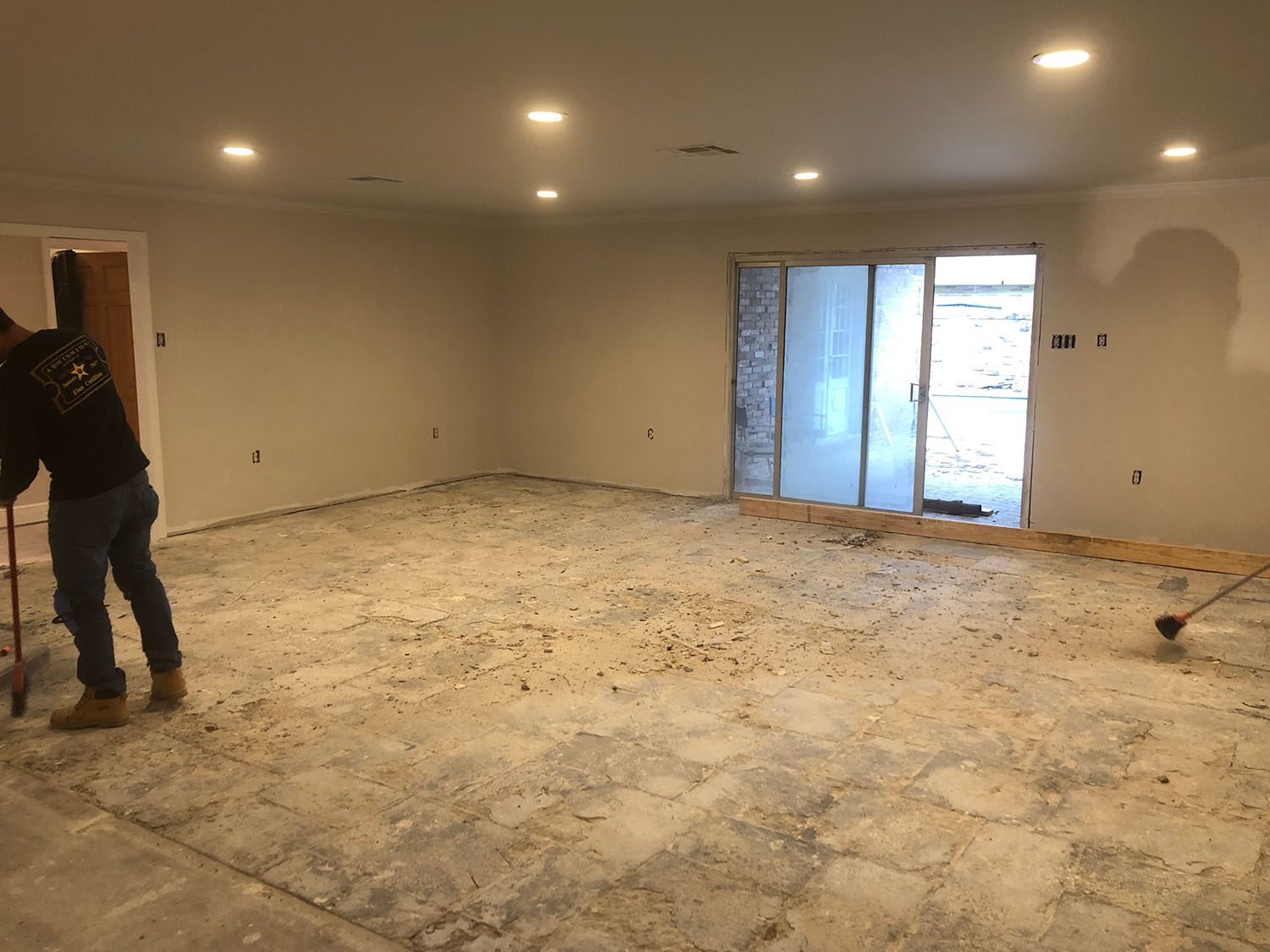 Empty room with bare floor and sliding glass doors.