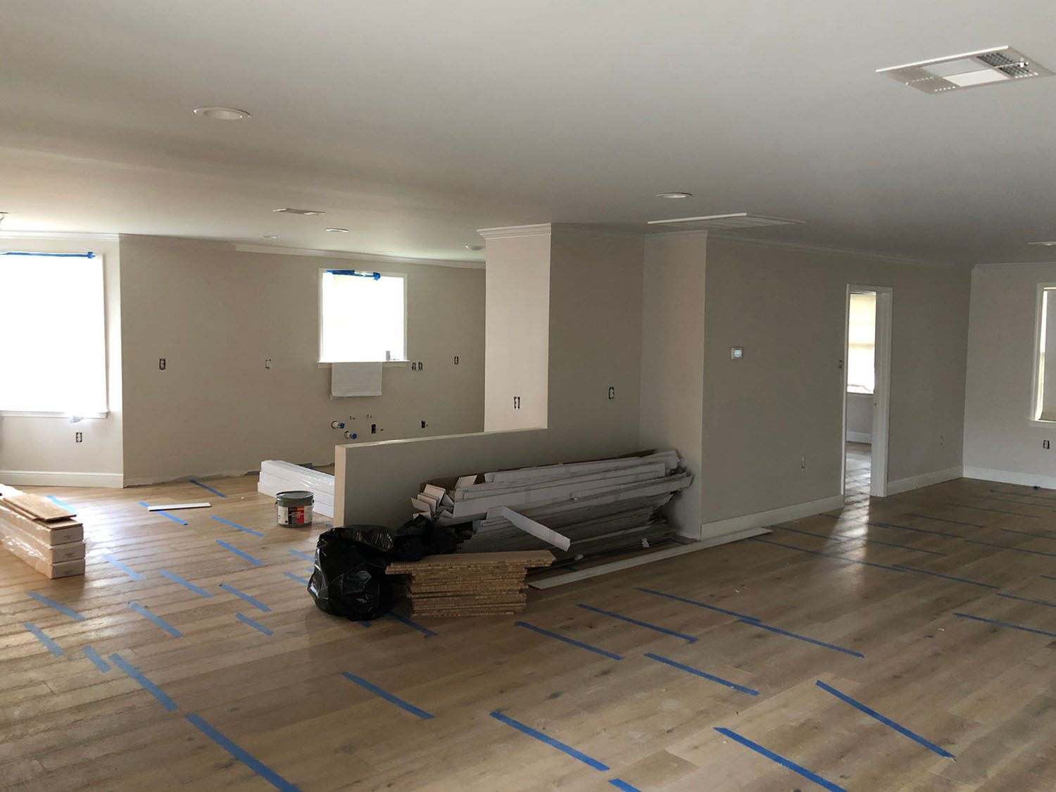 Empty room under renovation with protective floor covering and tools.